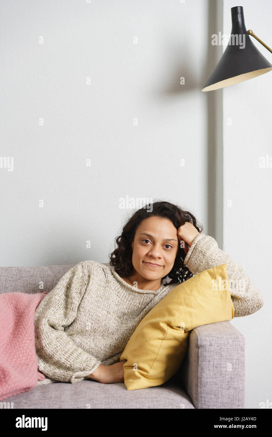 Portrait of smiling woman relaxing on sofa at home Stock Photo - Alamy