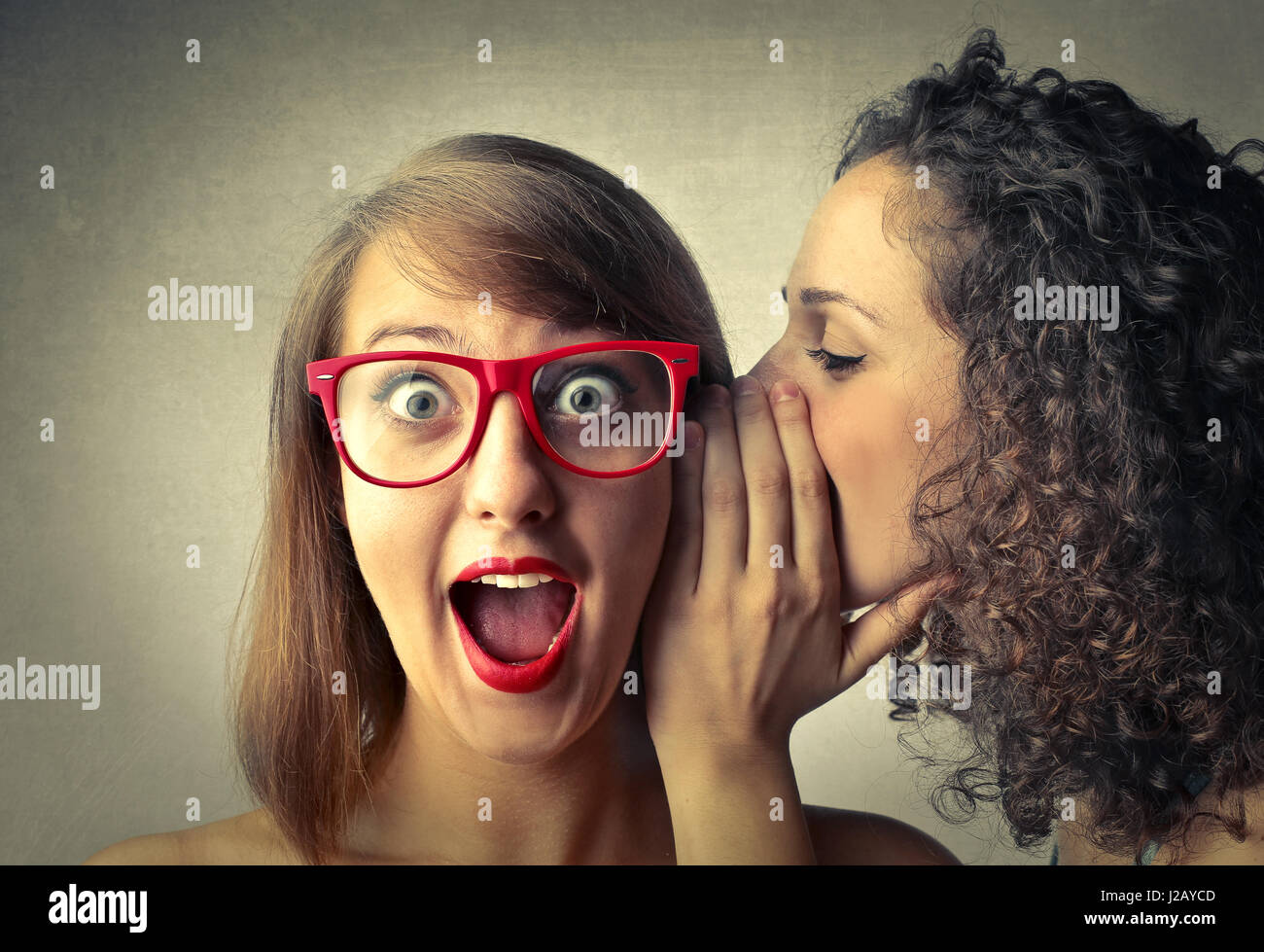 Woman whispering to other woman Stock Photo