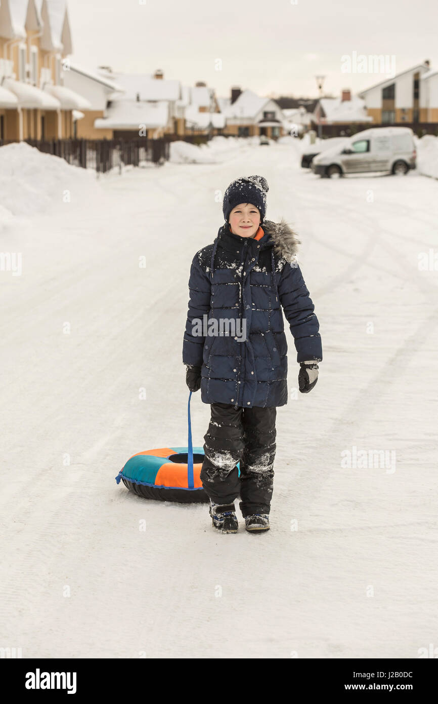 Full length portrait of boy pulling inflatable ring in snow Stock Photo