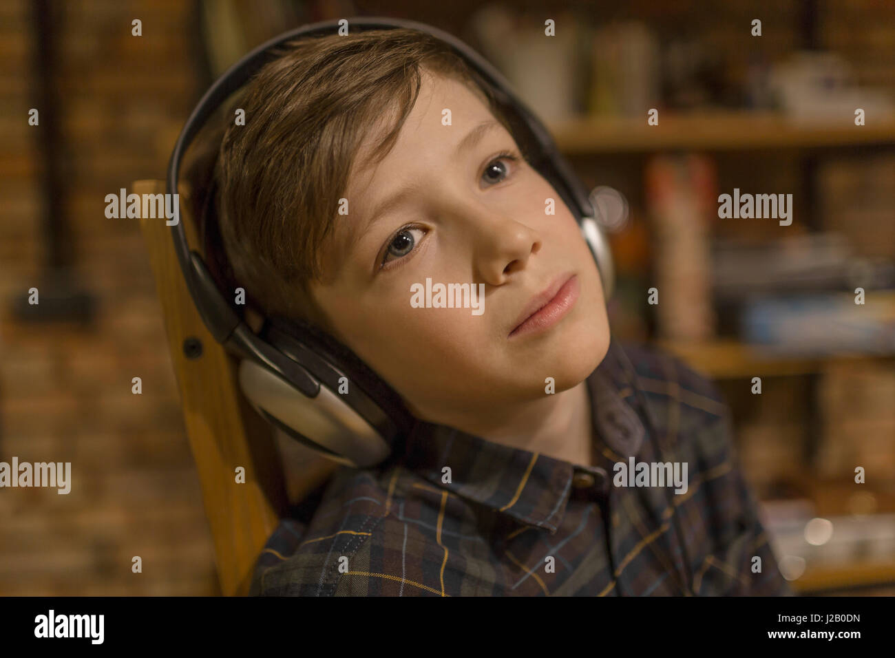 Thoughtful boy listening music through headphones at home Stock Photo