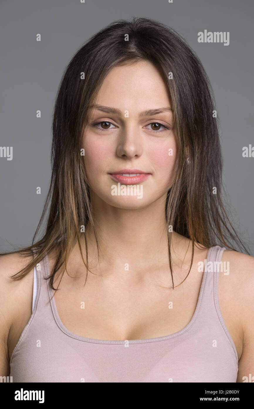 Close-up portrait of beautiful young woman against gray background ...