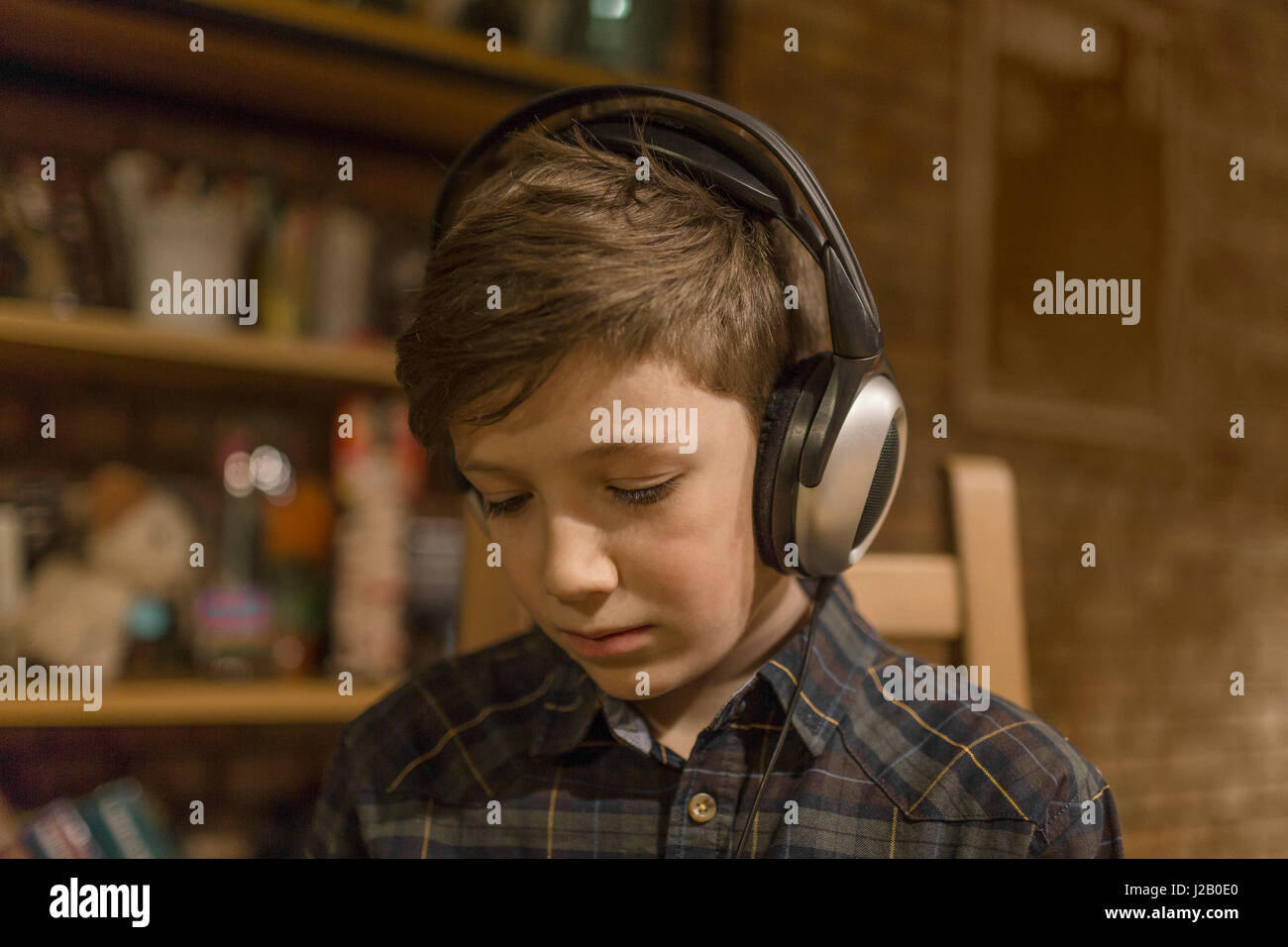 Boy listening music through headphones at home Stock Photo