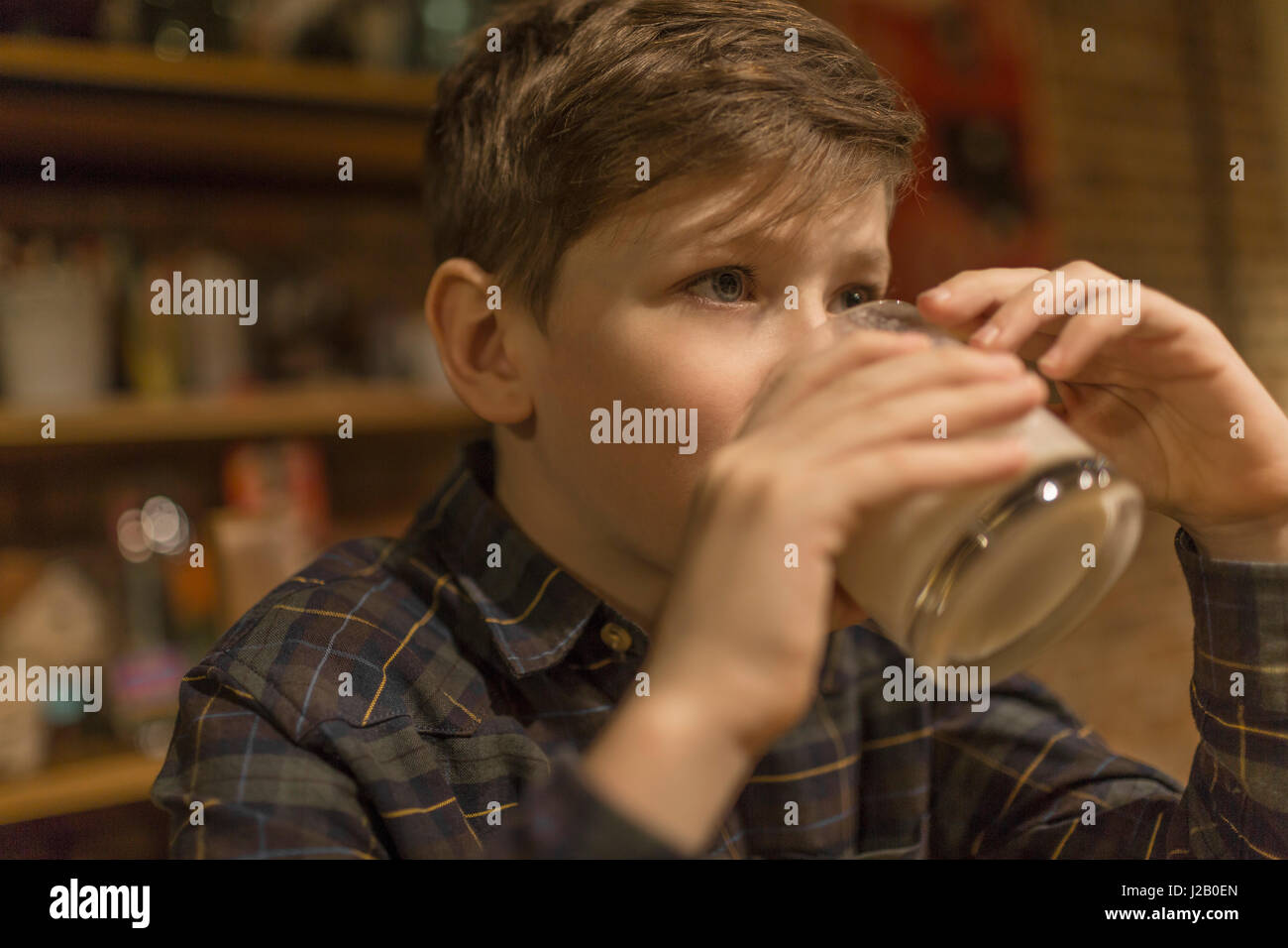 Boy looking away while drinking milk at home Stock Photo