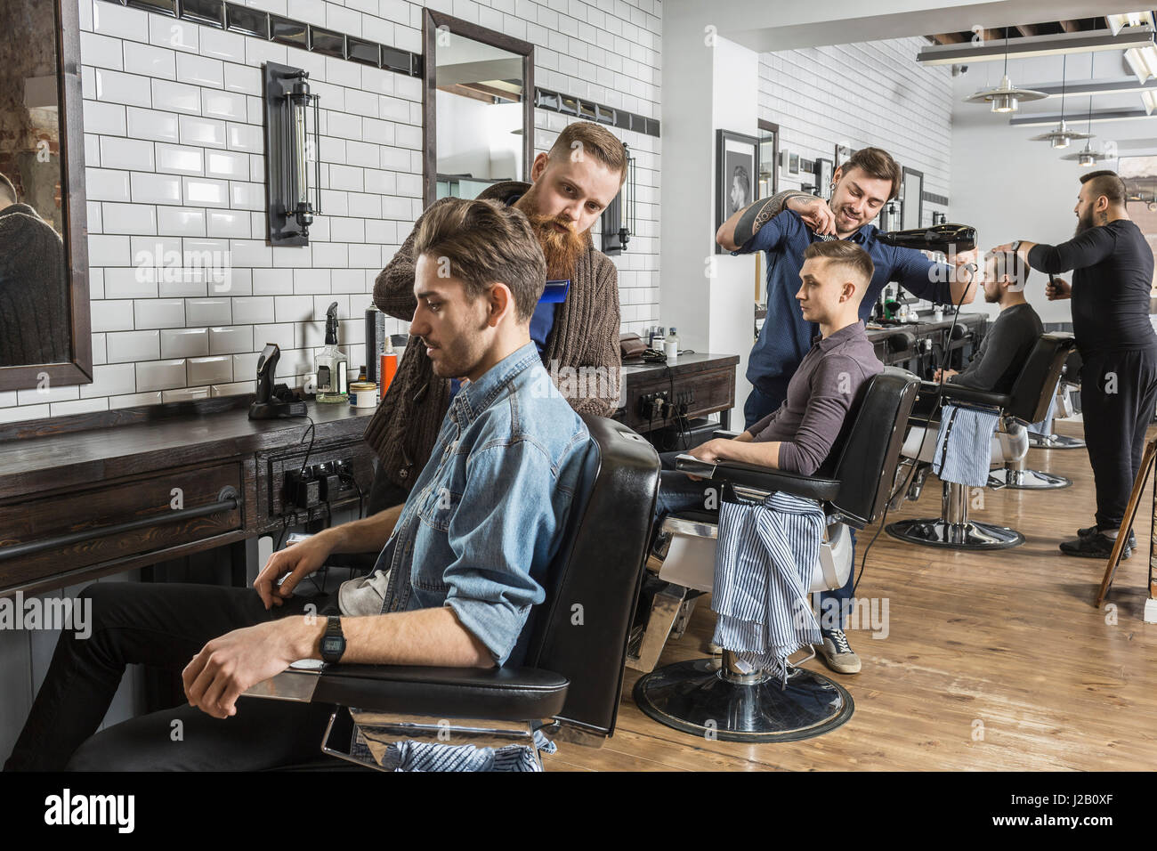 Hairdressers cutting male customer's hair in salon Stock Photo