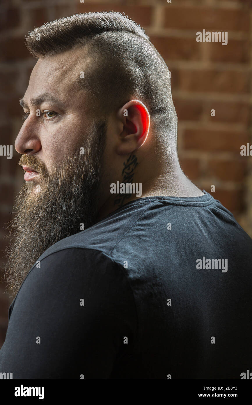 Close-up of male hairdresser with beard looking away at barber shop Stock Photo