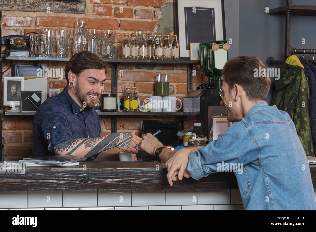 Cheerful male barbers sitting at bar counter in hair salon Stock Photo