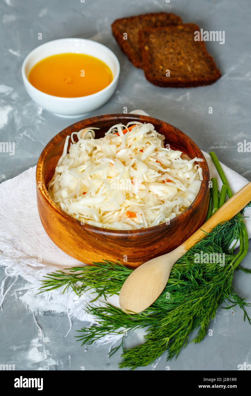 Sauerkraut in wooden bowl with bread, oil and dill. Love for a healthy vegan food concept Stock Photo