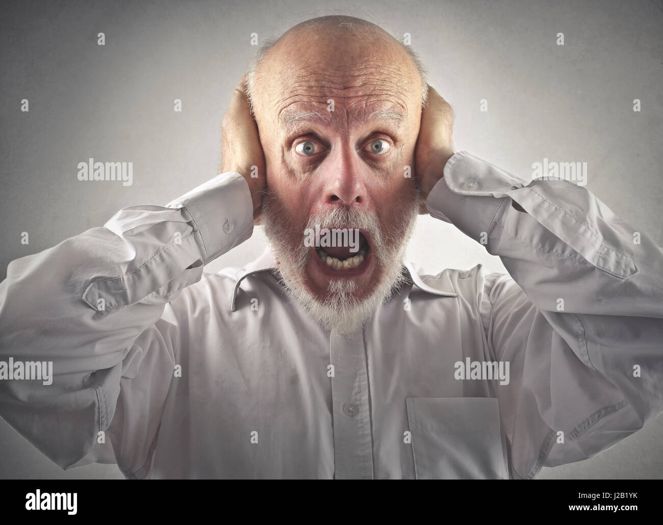 Scared old man covering his ears Stock Photo