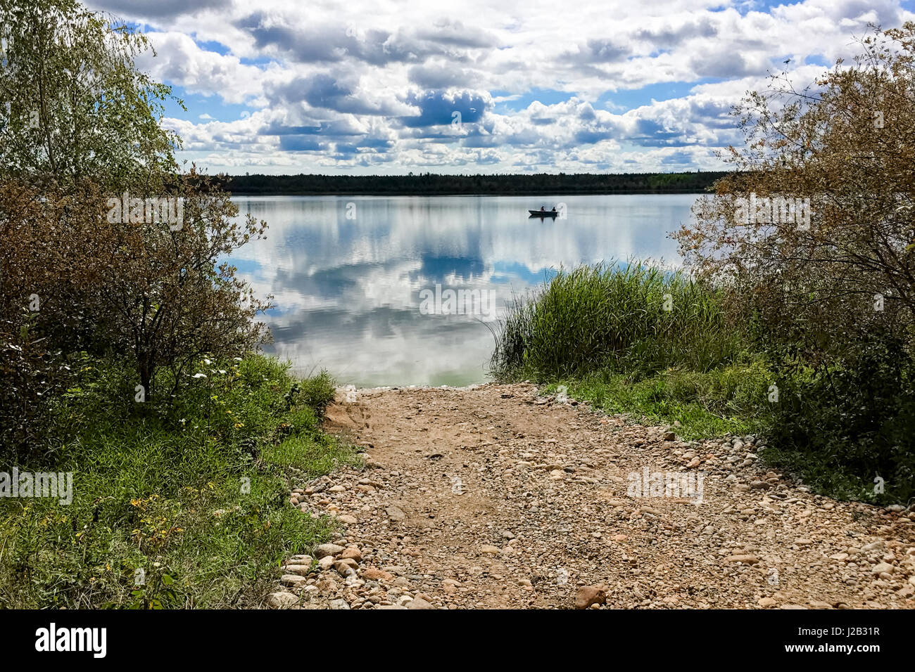 A fishing boat silhouetted on a calm lake Stock Photo - Alamy