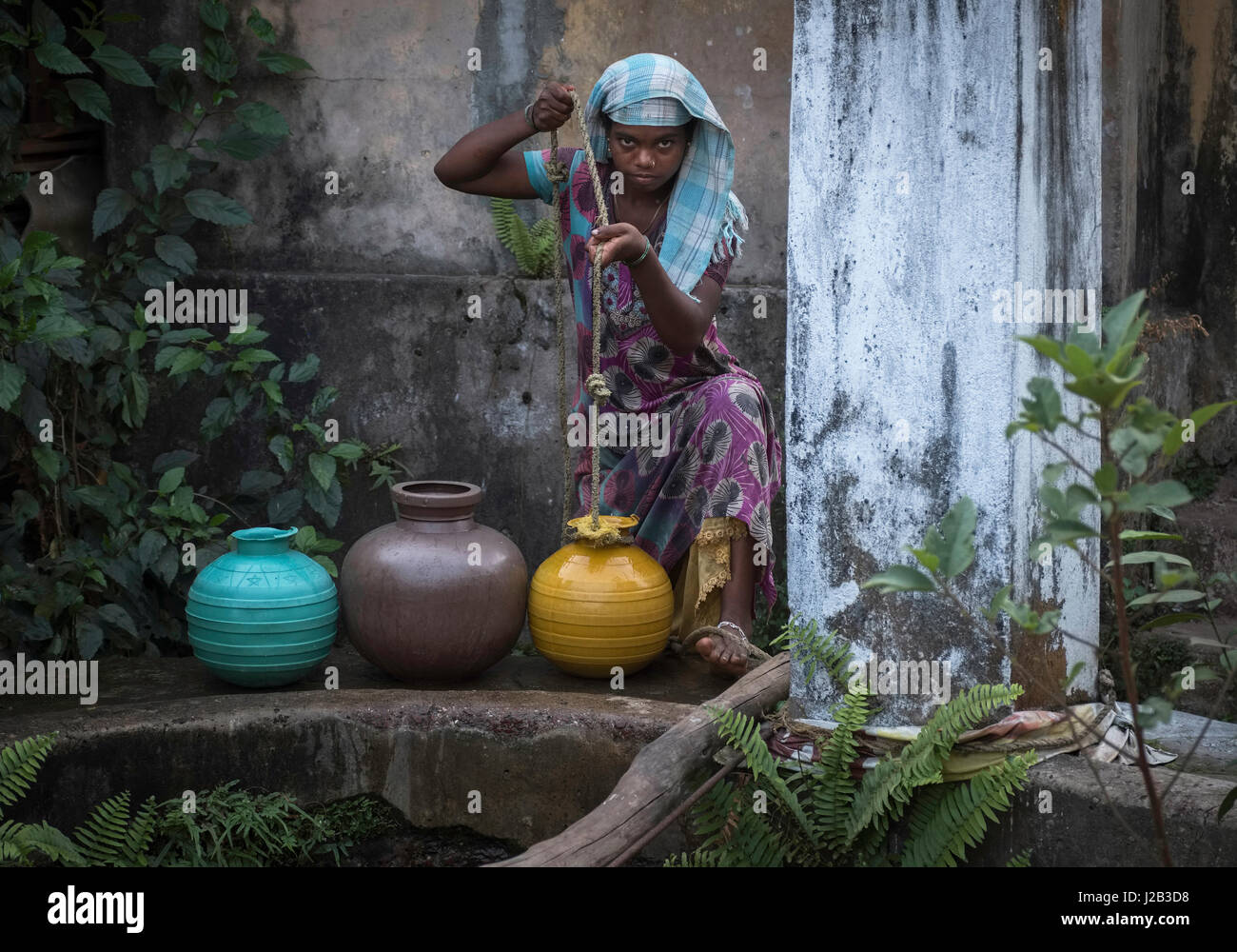 A young woman draws water from a well for use in cement making in a building Stock Photo