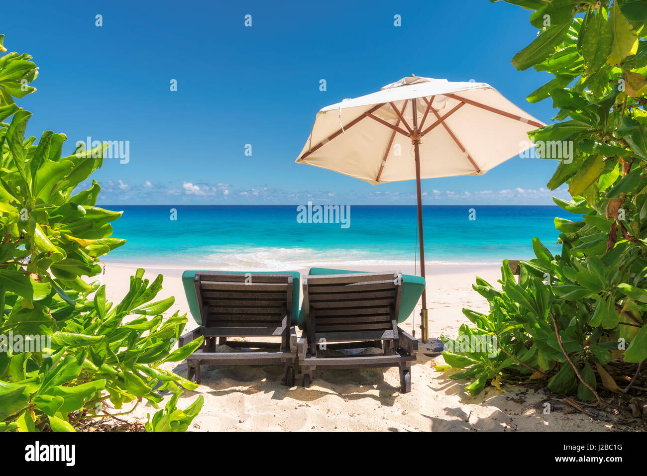 View over the amazing ocean beach with white sand, transparent turquoise water and umbrella and beach chair. Stock Photo