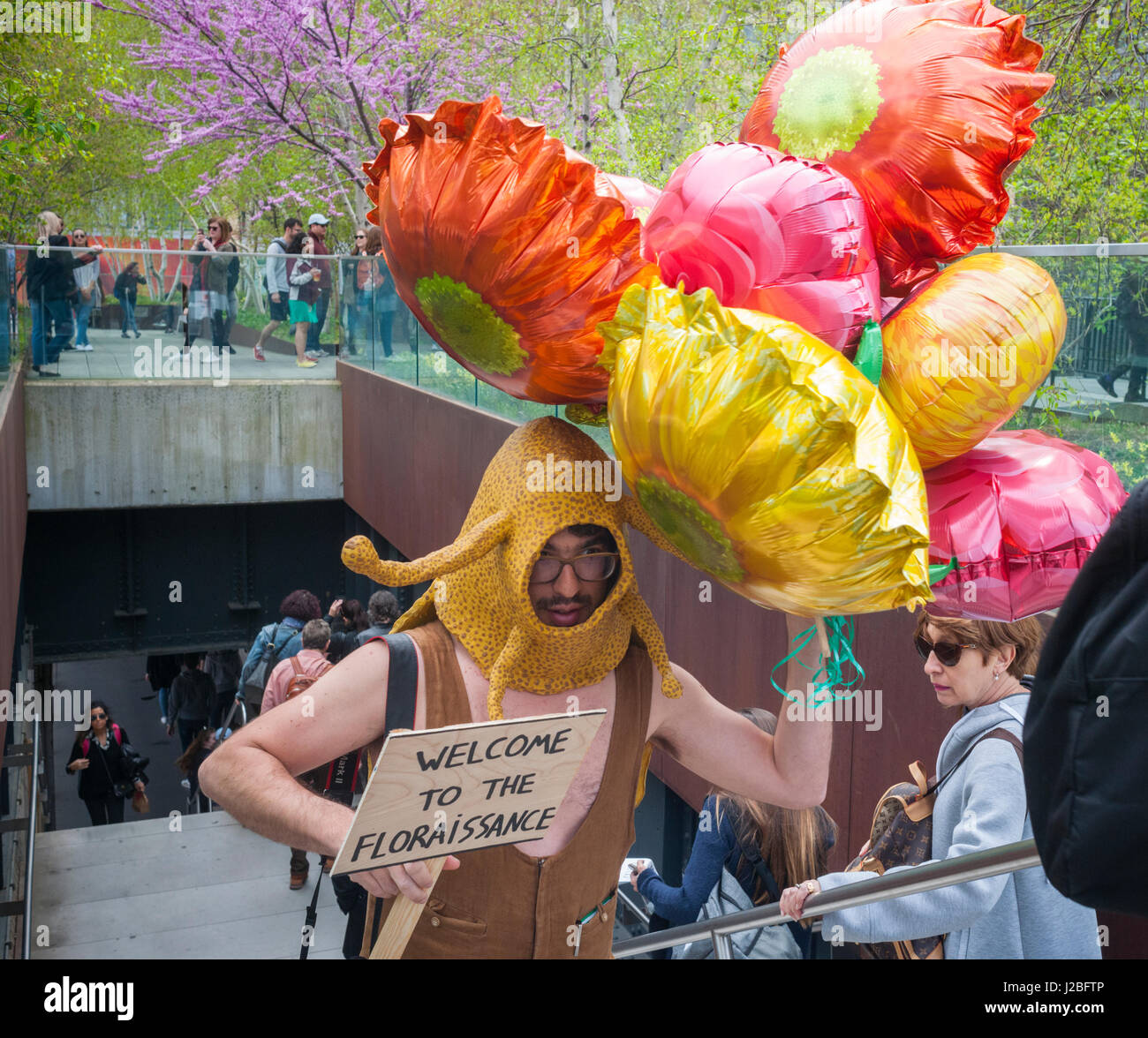 The Brazilian artist, André Feliciano known as the 'art gardener' walks down the High Line Park in New York on Sunday, April 23, 2017 distributing balloons and flowers to passer-by in his performance art piece, the Floraissance parade. The Floraissance is an art movement created by Feliciano based on the idea that contemporary cannot describe art anymore and we art moving into the next phase, growing like flowers, into the Floraissance. (© Richard B. Levine) Stock Photo