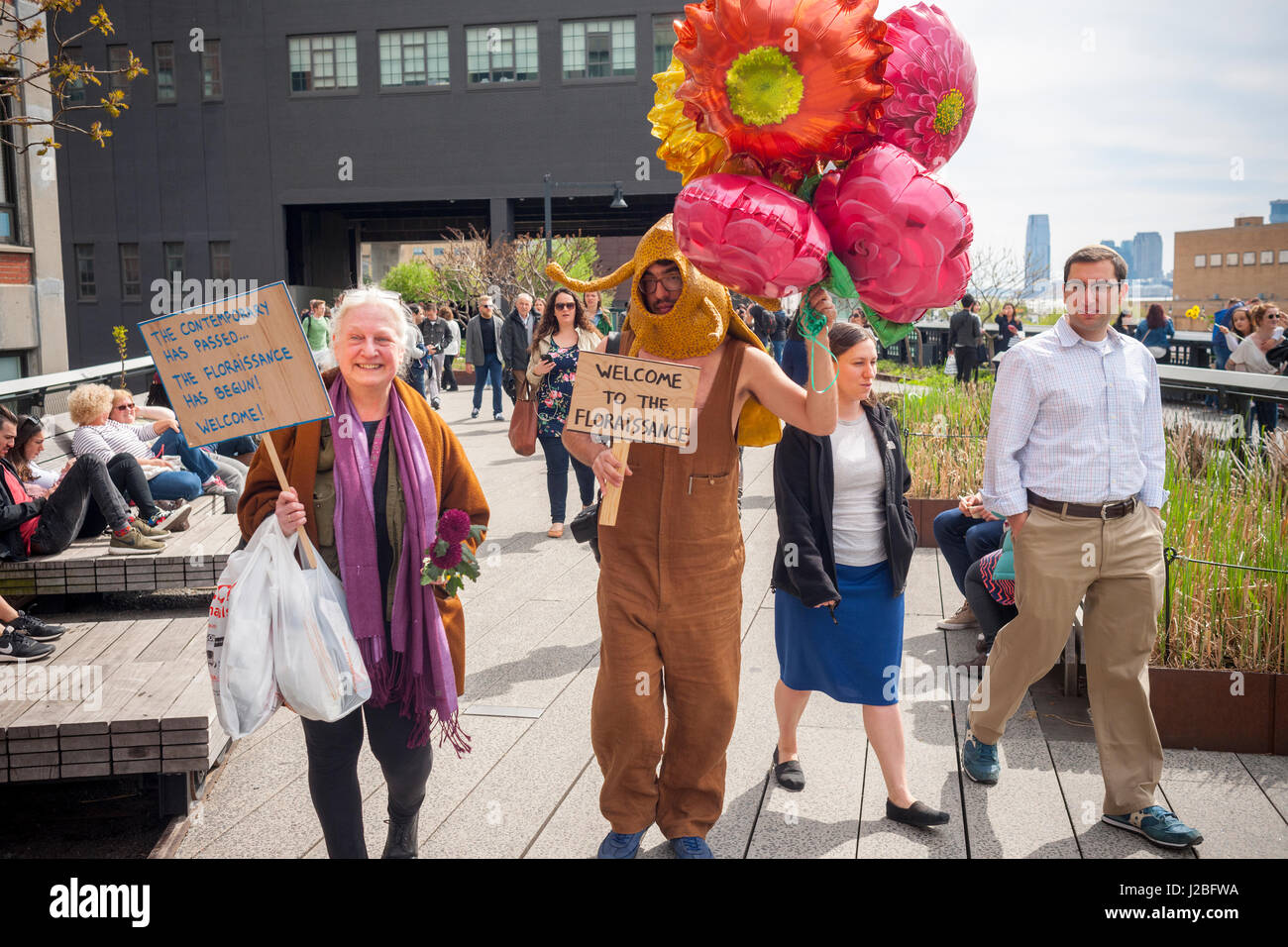 The Brazilian artist, André Feliciano, right, known as the 'art gardener' walks down the High Line Park in New York assisted by artist Nancy Prusinowski, left, on Sunday, April 23, 2017 distributing balloons and flowers to passer-by in his performance art piece, the Floraissance parade. The Floraissance is an art movement created by Feliciano based on the idea that contemporary cannot describe art anymore and we art moving into the next phase, growing like flowers, into the Floraissance. (© Richard B. Levine) Stock Photo