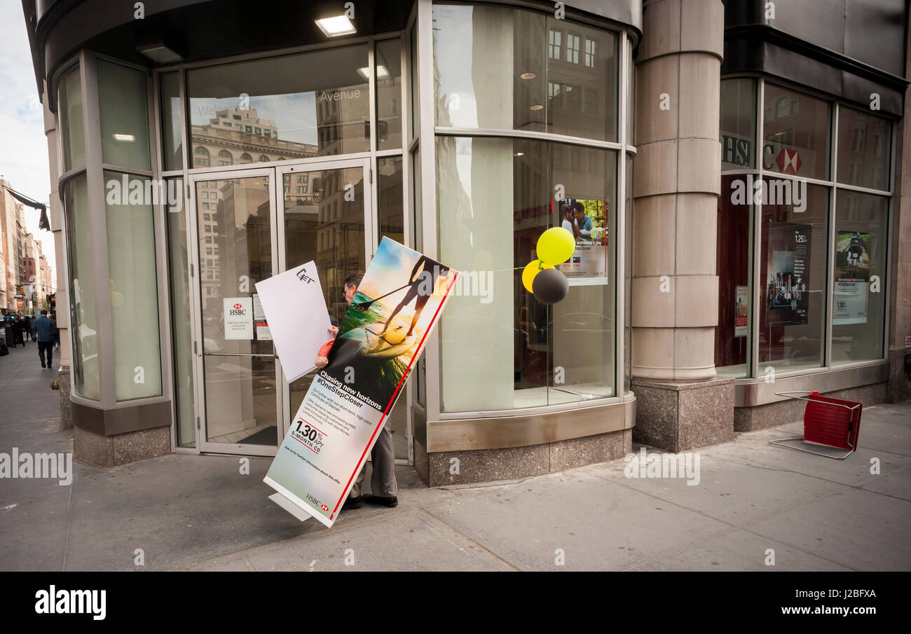 An HSBC bank branch employee in the Flatiron neighborhood of New York removes a promotional board from outside the bank on Monday, April 17, 2017.  (© Richard B. Levine) Stock Photo