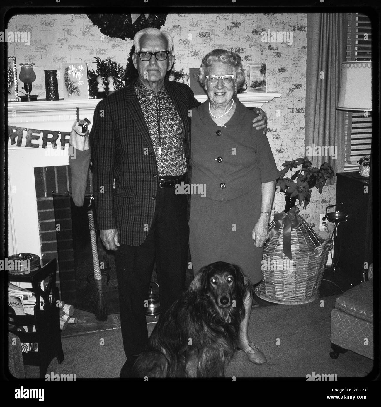 Slides 35 mm to photograph. Older couple in the 1960's standing as a family in front of fireplace at Christmas. Old style, vintage type. Stock Photo