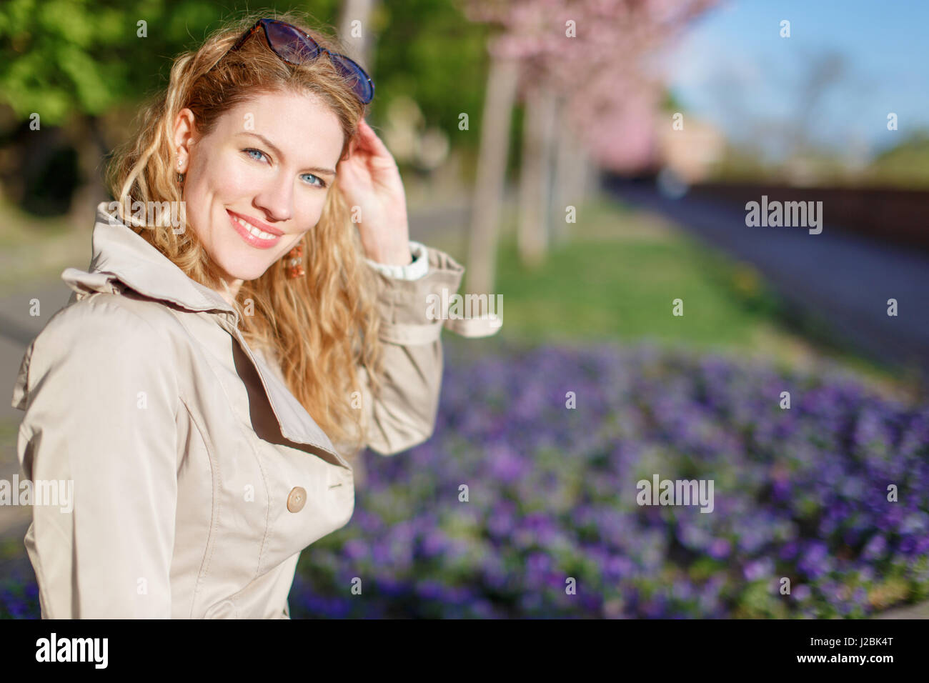 Young natural woman holding sunglasses in park at spring Stock Photo
