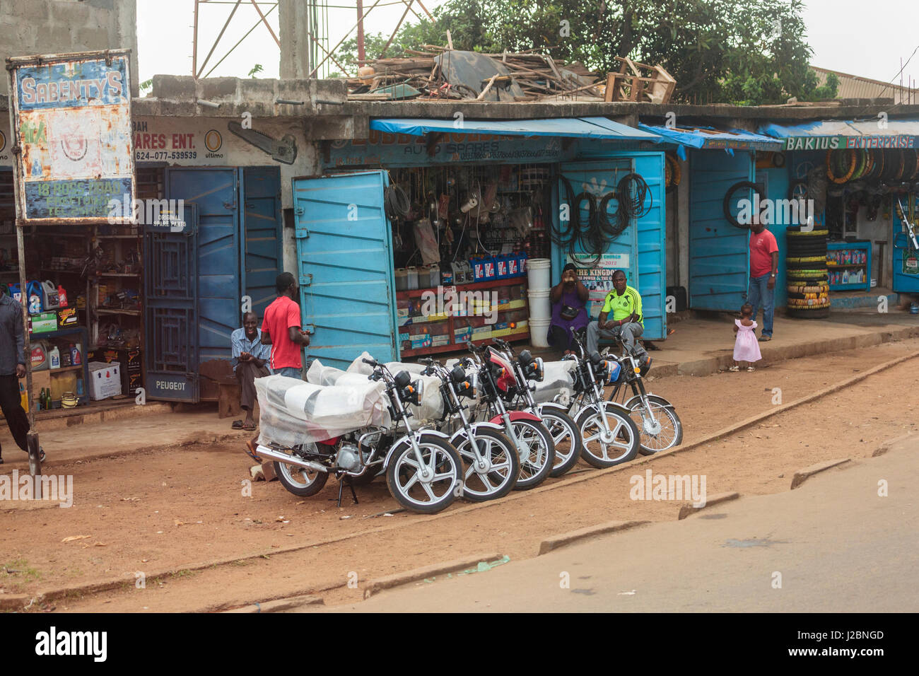 Africa, Sierra Leone, Freetown. A set of motorcycles available for sale in front of stores selling replacement parts. Stock Photo