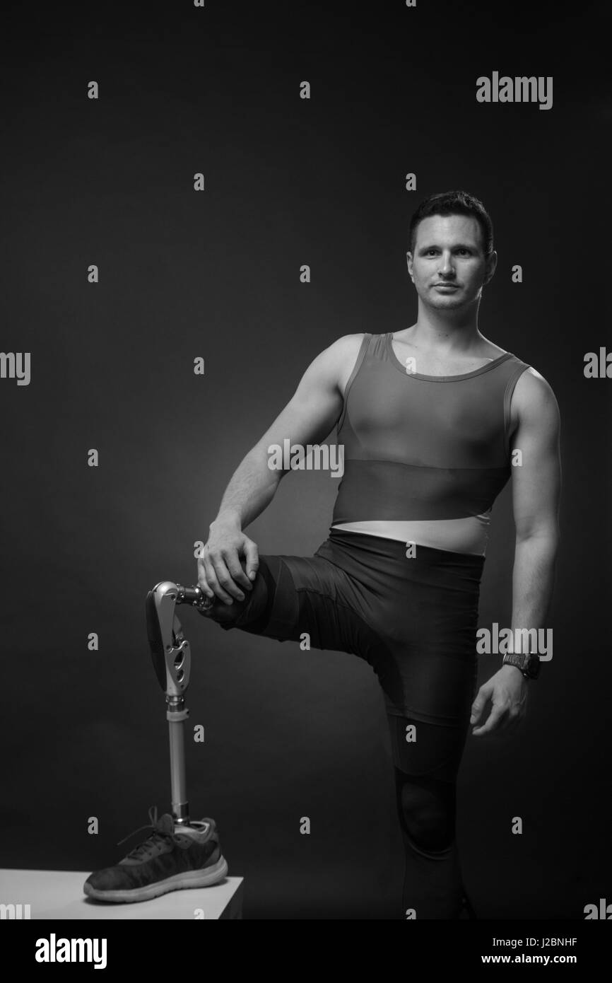 one young adult man disabled, sportsman athlete posing, one prosthetic leg, standing, black and white Stock Photo
