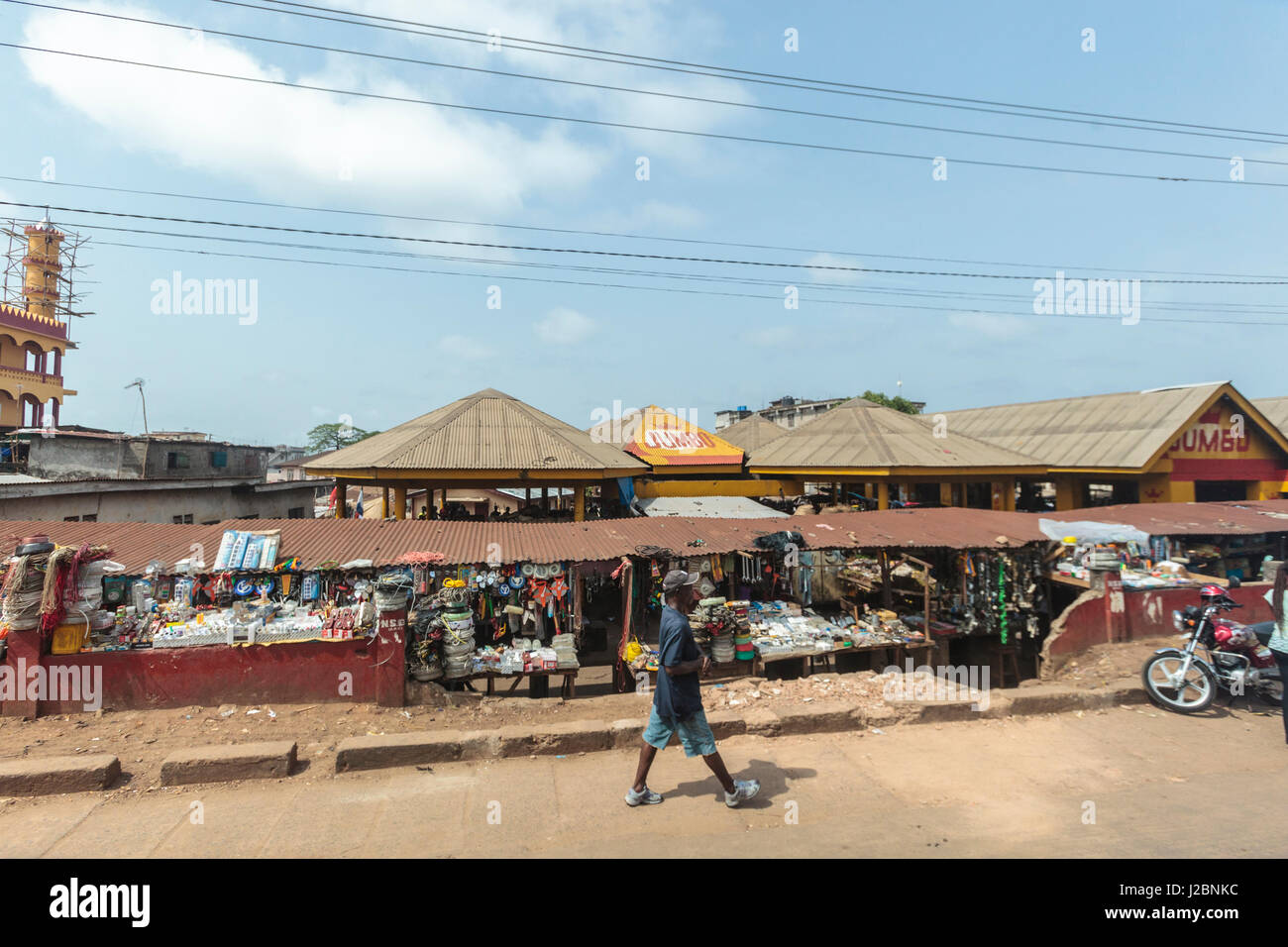 Africa, Sierra Leone, Freetown. A man walking past a market. Stock Photo