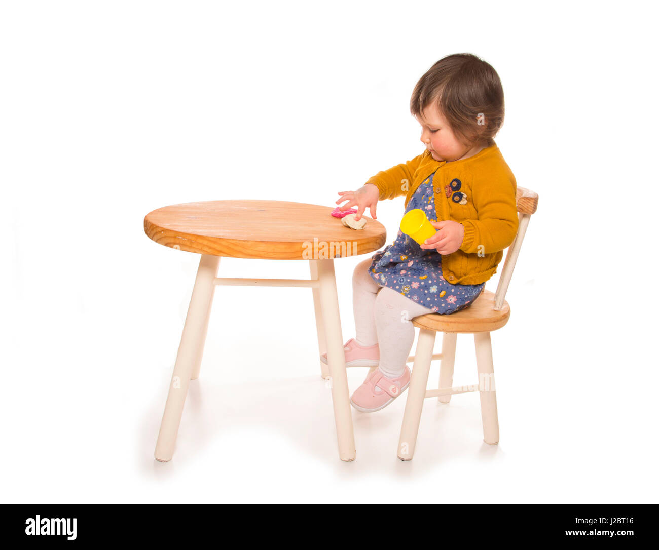 Toddler Sitting At A Table Playing With Playdough Cutout