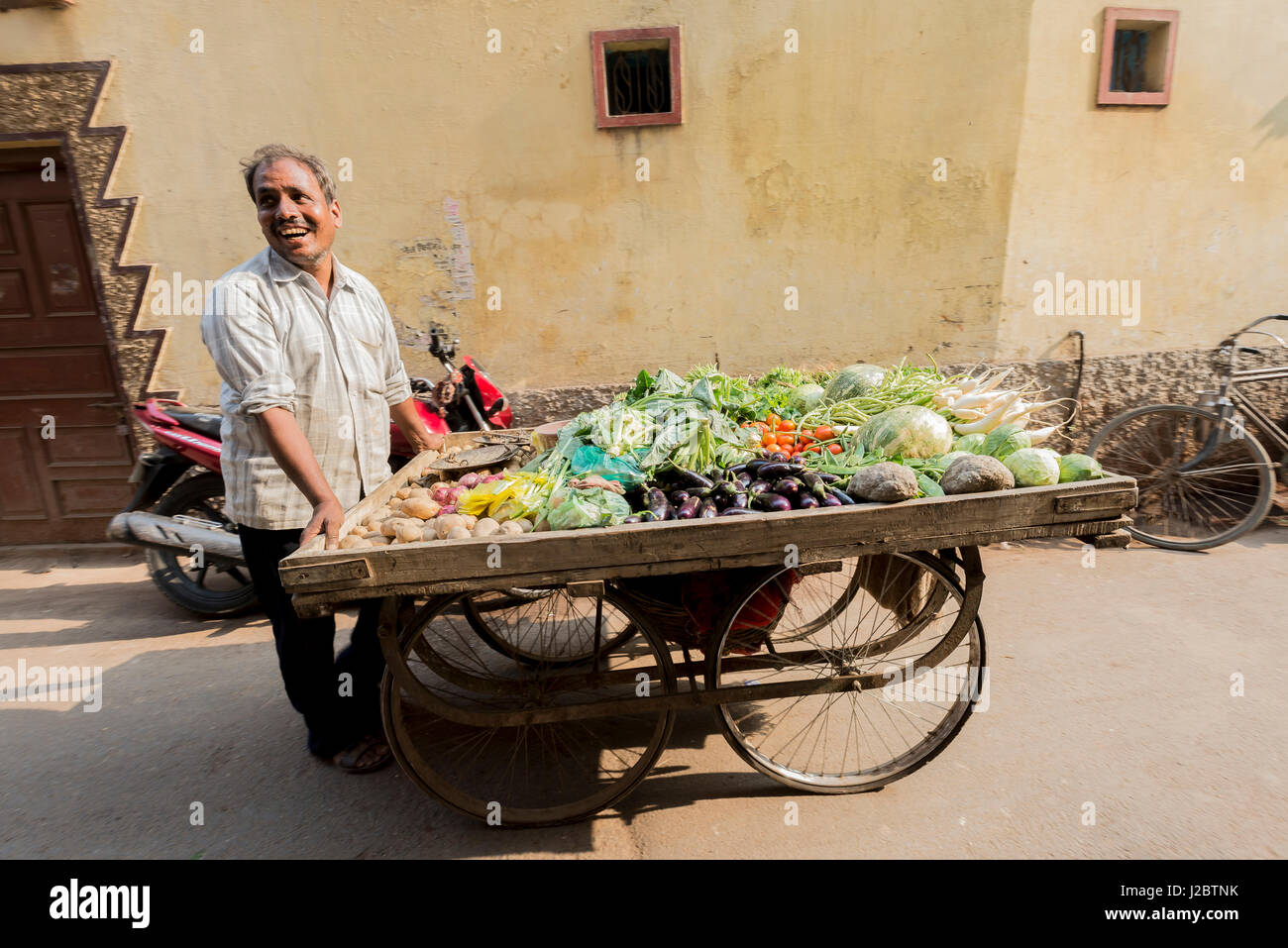 India, Varanasi a smiling vegetable seller with his cart of fresh