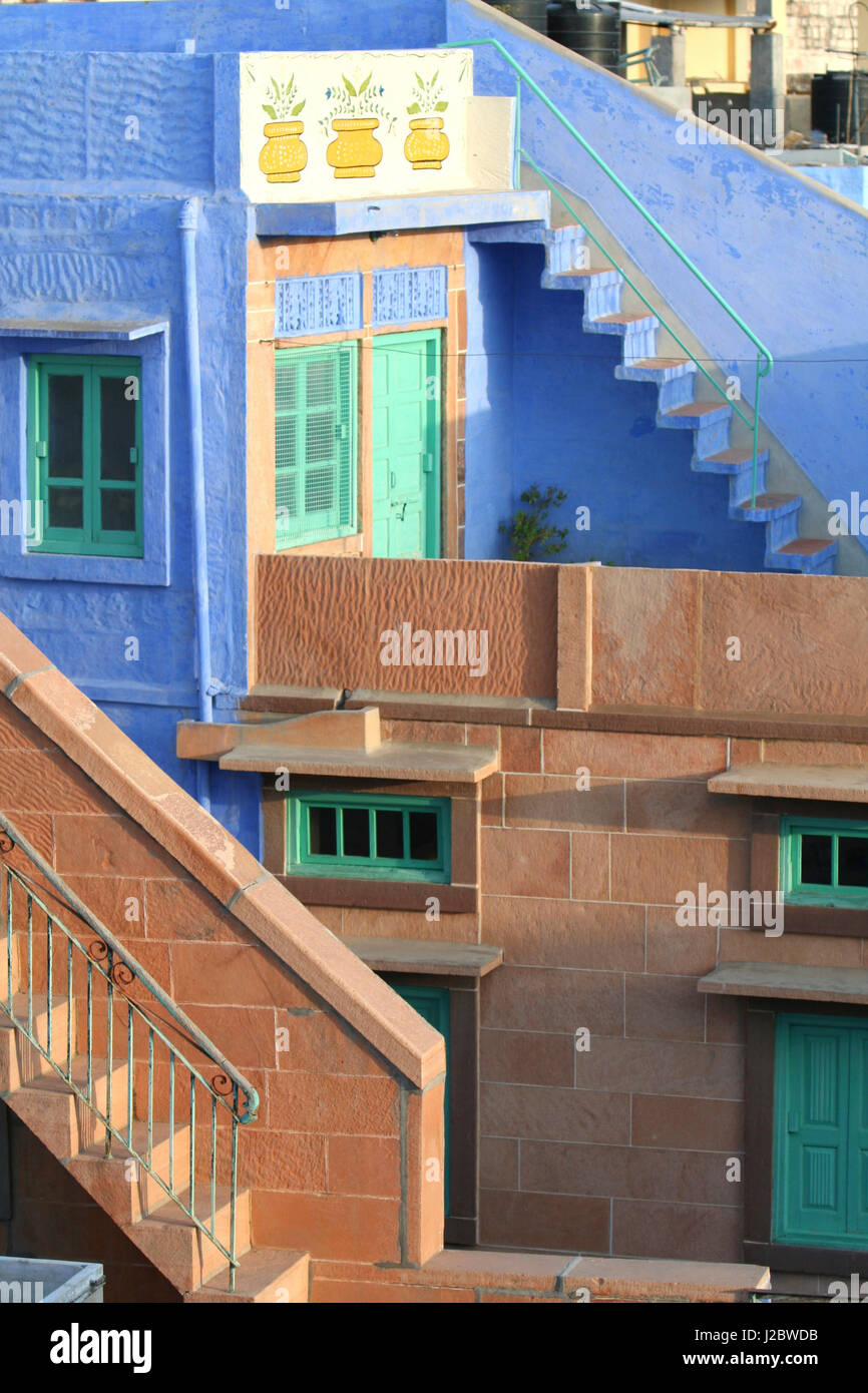 Blue City, Jodhpur, India. Blue apartment with a teal, green door, and painted flower pots, and a brick stairwell Stock Photo