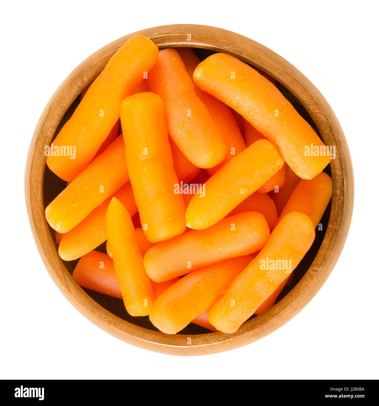 Baby carrots in wooden bowl. Cooked small sized and immature carrots. Root vegetable with orange color. Daucus carota. Isolated macro photo. Stock Photo