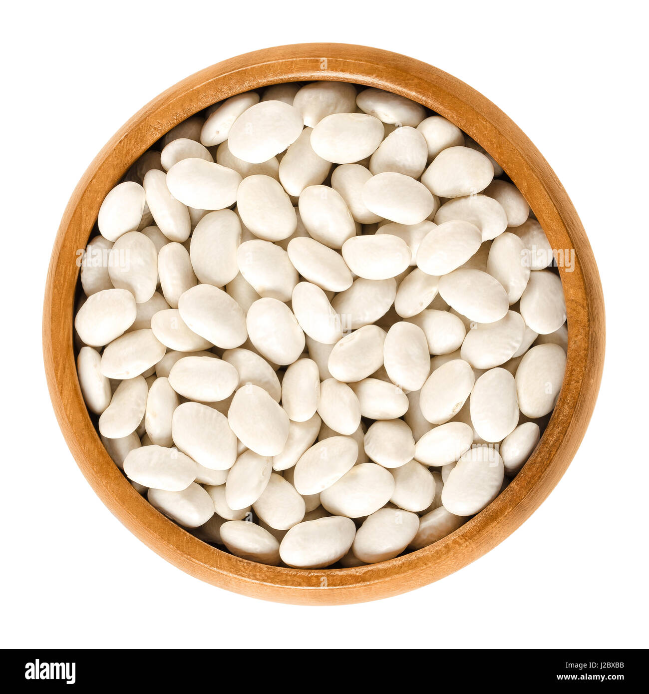 White navy beans in wooden bowl, also haricot, pearl haricot, boston, white or pea bean. Dried seeds of Phaseolus vulgaris, a legume. Stock Photo
