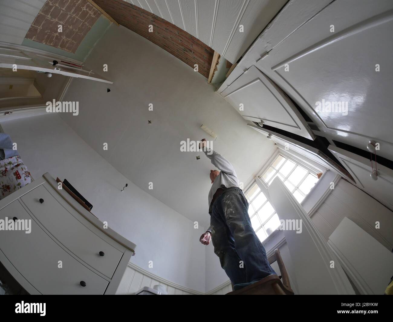 man painting bathroom ceiling Stock Photo