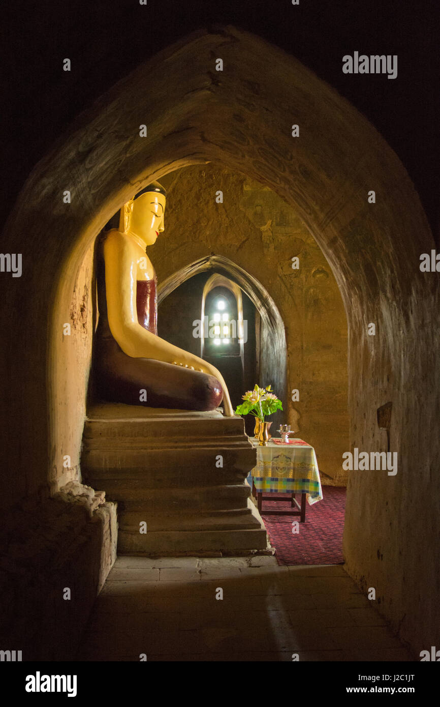 Myanmar. Bagan. Buddha lit from the light of a stone divided window. Stock Photo