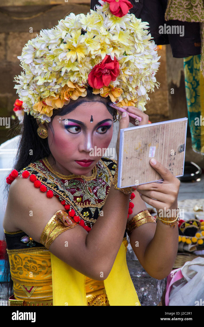 Indonesia, Bali. Female dancer getting her crown of Frangipani flowers adjusted and makeup applied before the Legong Dance. (Editorial Use Only) Stock Photo