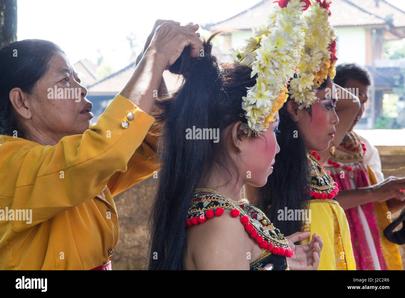Indonesia, Bali. Female performers getting their hair styled with Frangipani flowers before the Legong Dance. (Editorial Use Only) Stock Photo