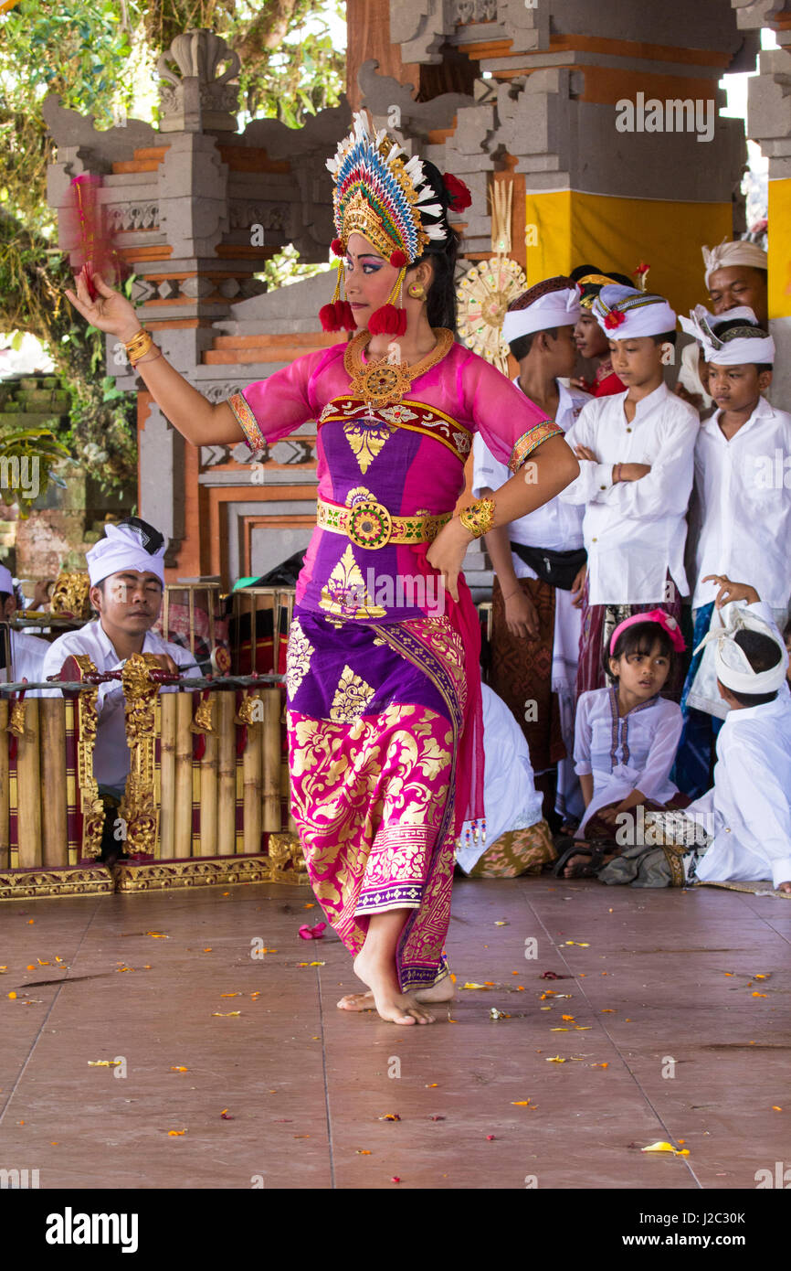 Indonesia, Bali. Dressed in Traditional Dancing Costume, Legong Dancer with Frangipani floral headdress, being watched by younger participants. (Editorial Use Only) Stock Photo