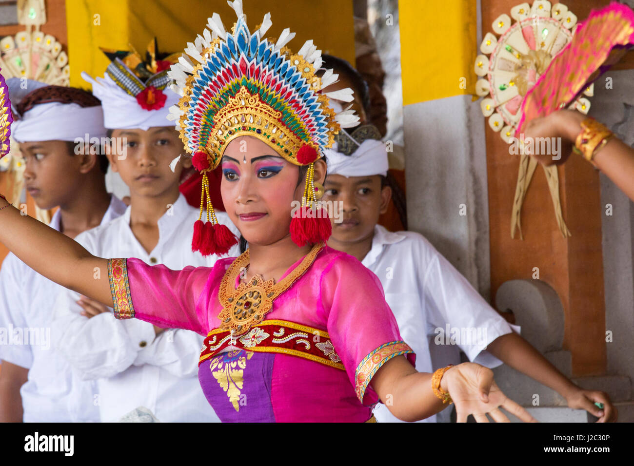 Indonesia, Bali. Dressed in Traditional Dancing Costume, Legong Dancer with Frangipani floral headdress, being watched by younger participants. (Editorial Use Only) Stock Photo