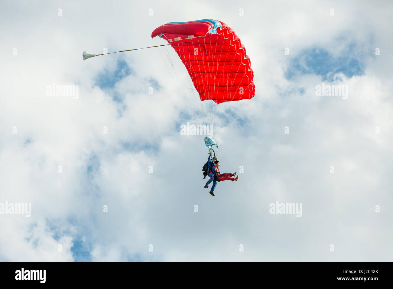 Pribram, CZE - August 19, 2016. Tandem red paraglider flying against the cloudy sky in Pribram airport, Czech Republic Stock Photo