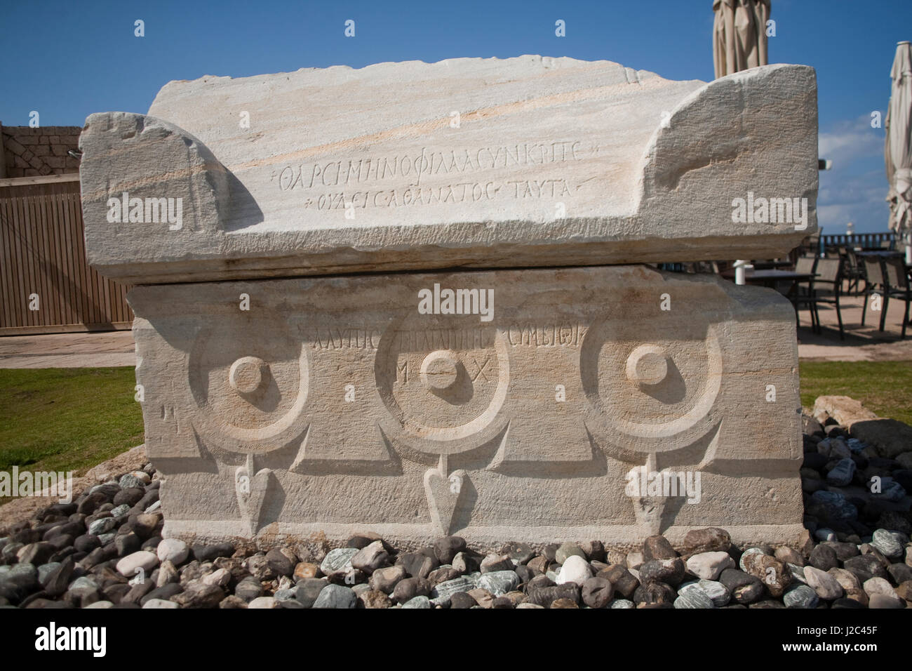 Ancient inscribed sarcophagus adorned with garlands on shoreline of Caesarea, Israel. Stock Photo