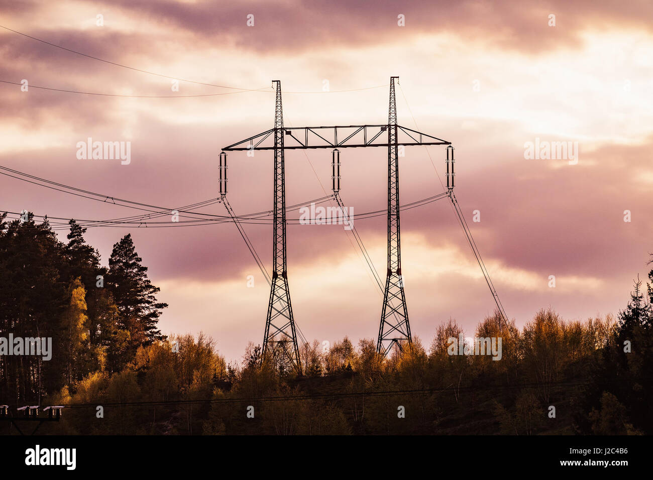 electricity transmission pylon silhouetted against red sky at dusk Stock Photo