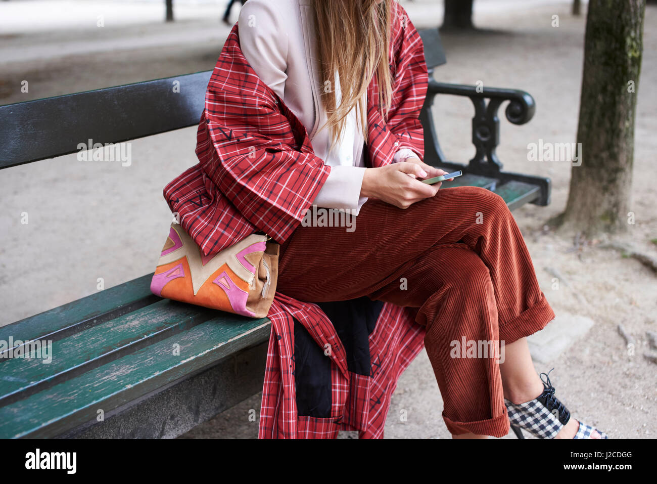 Fashionable woman sitting on bench using phone, crop Stock Photo