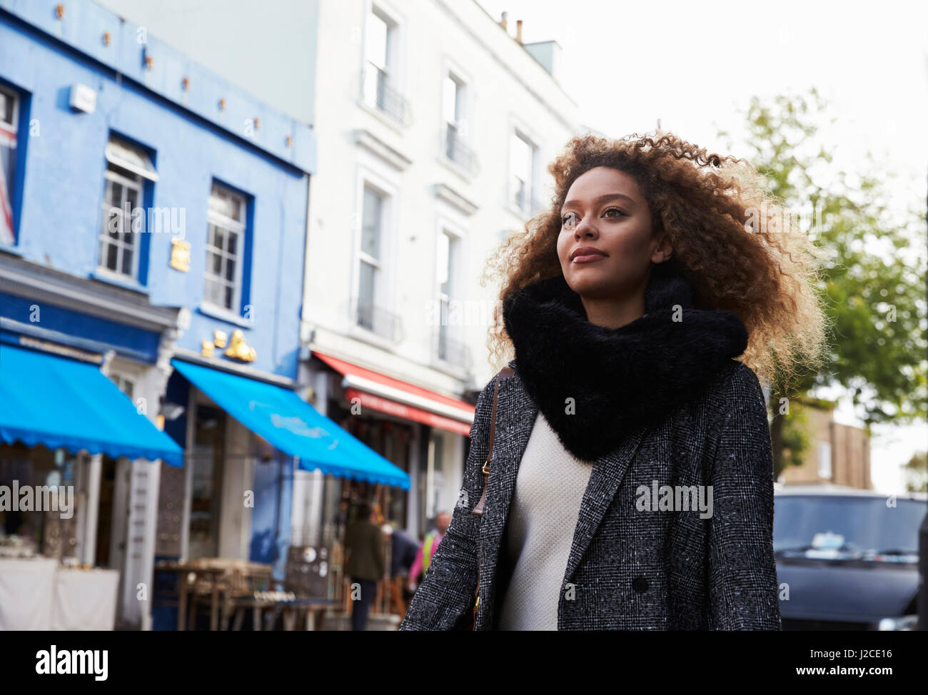 Stylish Young Woman Walking Along Busy City Street Stock Photo - Alamy