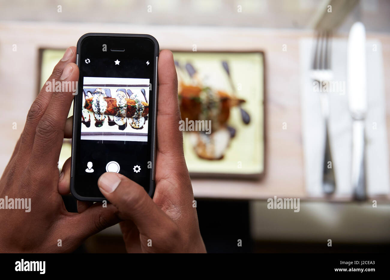 Food Blogger Taking Picture Of Meal In Restaurant On Mobile Stock Photo