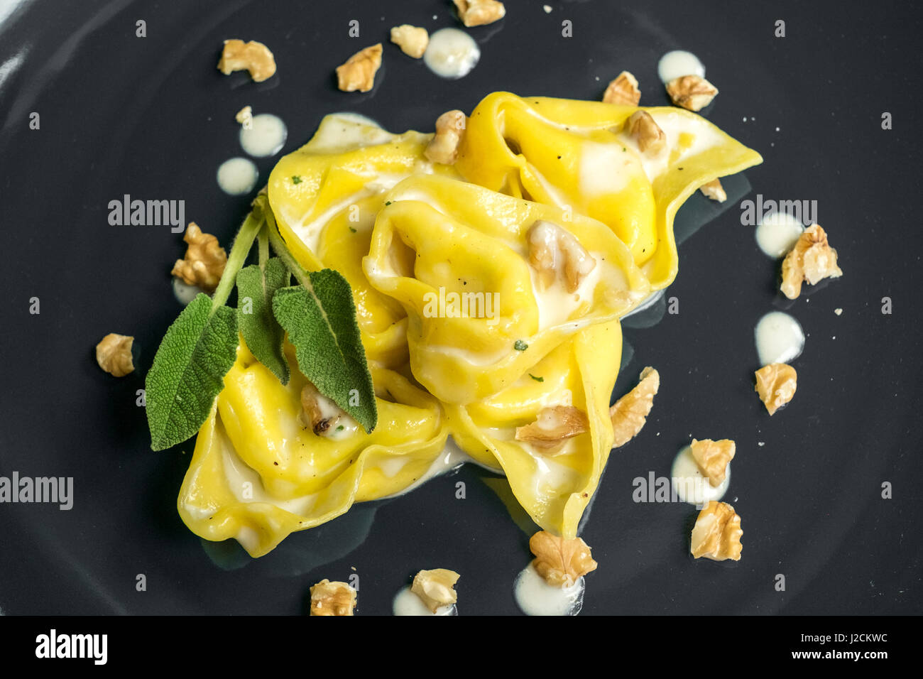Tortelloni, (homemade stuffed pasta) with nuts, cream and sage. Typical Bologna food. Stock Photo