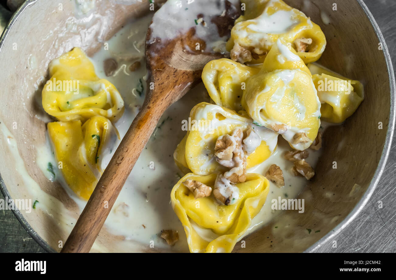 Tortellini (typical Bologna homemade stuffed pasta) with nuts, cream and sage in their cooking pan Stock Photo