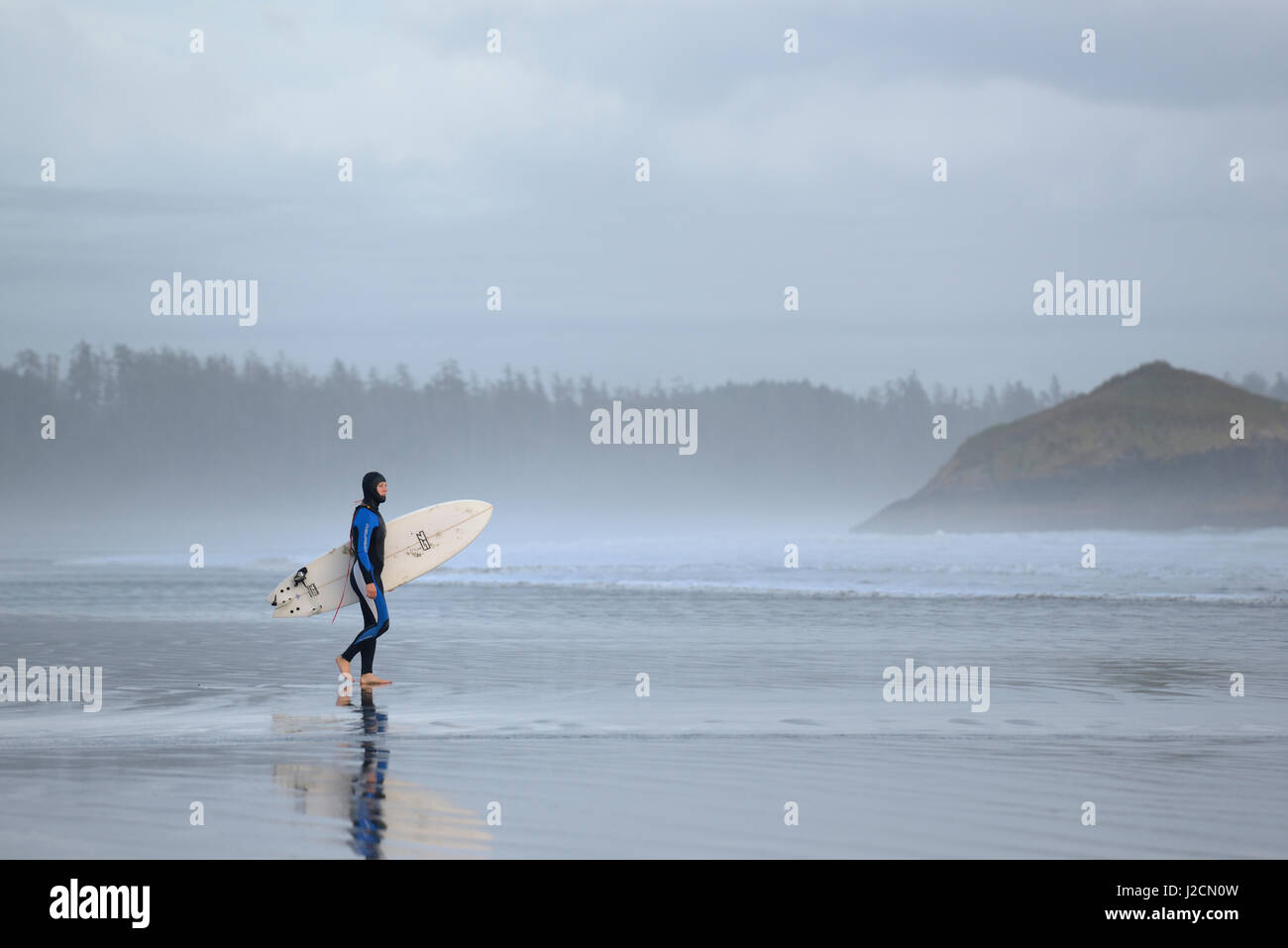 Canada, British Columbia, Vancouver Island. Man in wetsuit walking with