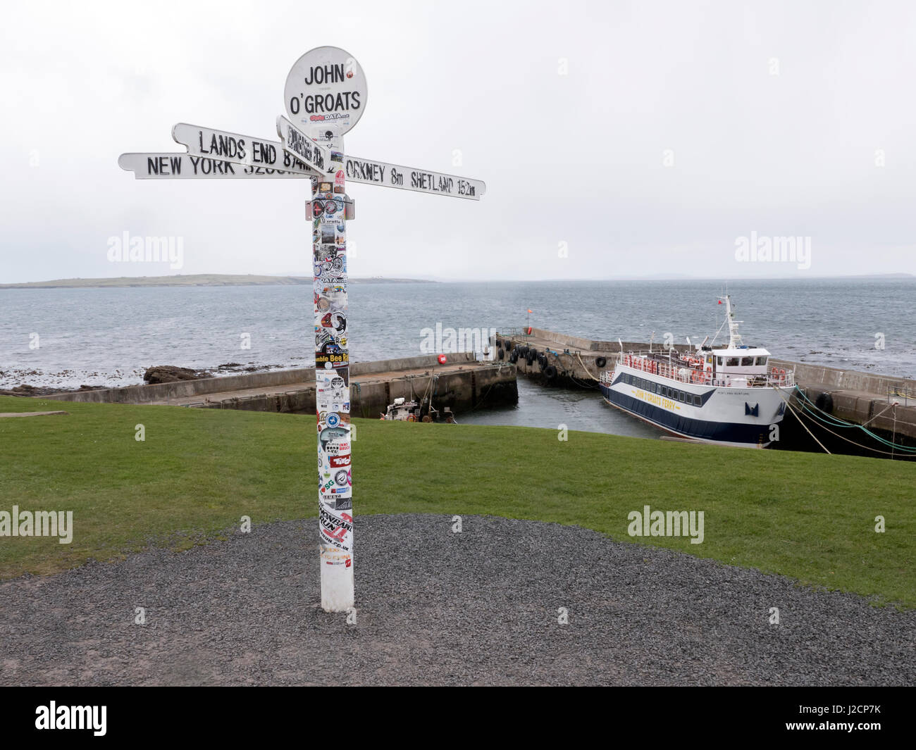 John O'Groats signpost with Orkney Ferry in the harbour behind Stock Photo