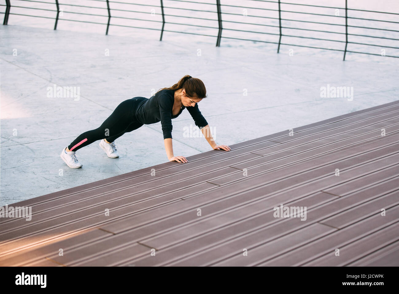 Beautiful fitness woman doing push ups during outdoor training workout ...