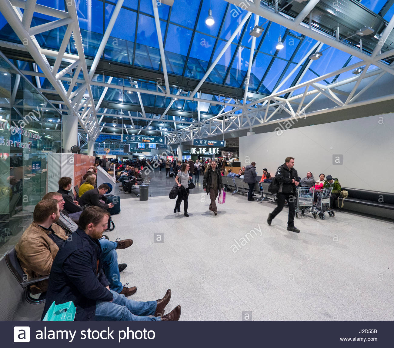 People Walking Under Glass Ceiling In Departure Terminal At The