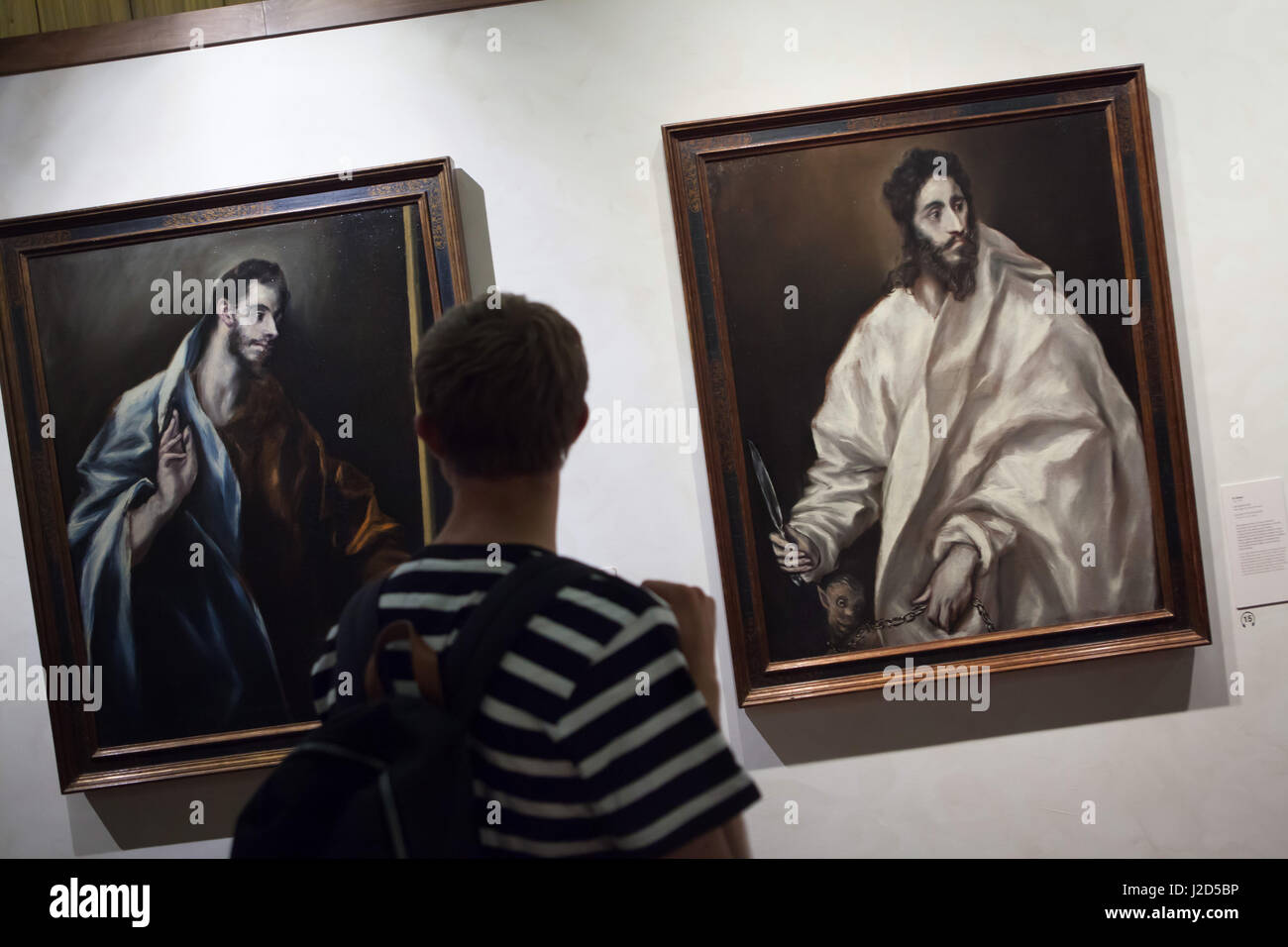 Visitor in front of the paintings of Saint Thomas the Apostle (L) and Saint Bartholomew the Apostle (R) from the Apostolados (1610-1614) by Spanish mannerist painter El Greco displayed in the El Greco Museum in Toledo, Spain. Stock Photo