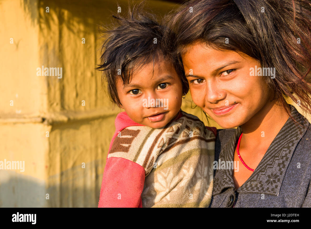 Portaits of a local woman and her child in front of a typical farm house in the village Pandavnagar in Chitwan National Park Stock Photo