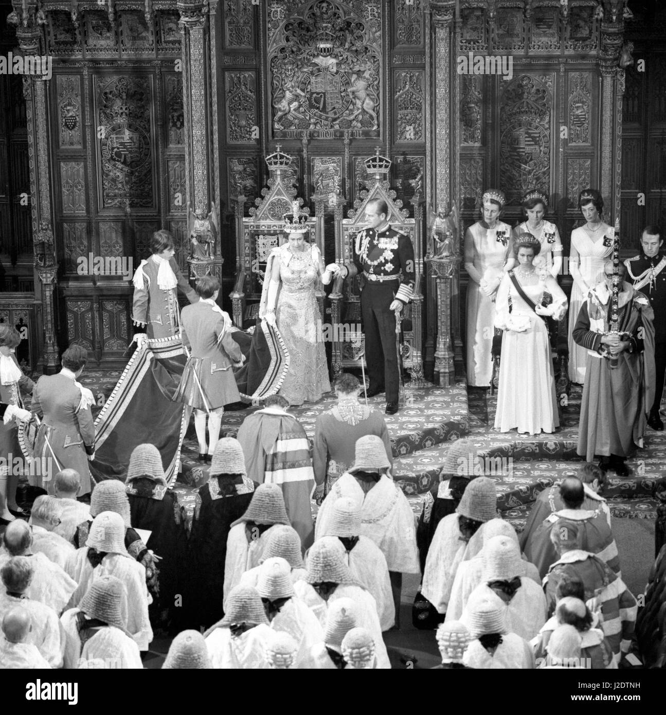 The pages of honour lift the train of Queen Elizabeth II's robes as she and Prince Philip, Duke of Edinburgh, takes her hand to raise her from her throne after her speech at the State Opening of Parliament in the chamber of the House of Lords. Also in the image are Princess Anne (foreground right), her husband Captain Mark Phillips (extreme right), and The Sword of State, Marshal of the Royal Air Force the Lord Elworthy. Stock Photo