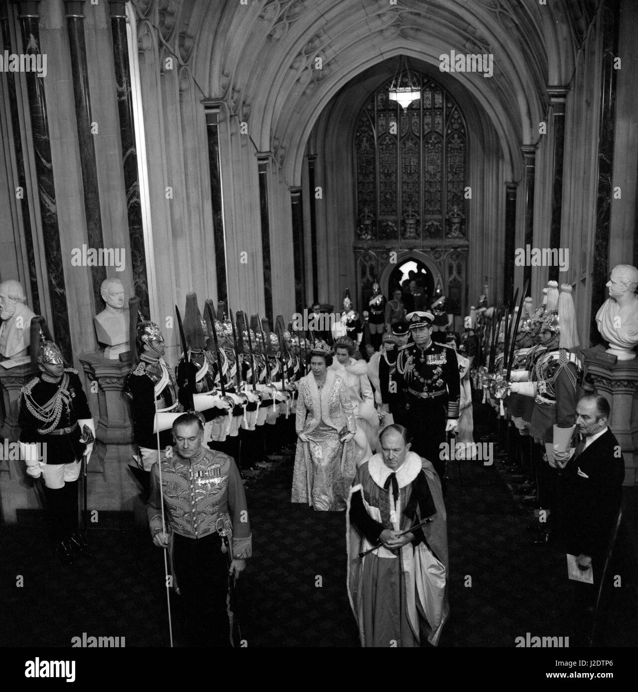 Wearing a golden tissue gown and a silver tissue coat, Queen Elizabeth II accompanied by Prince Philip, the Duke of Edinburgh, and followed by Princess Anne and Captain Mark Phillips, climbs the Norman Porch stairs of the Palace of Westminster for the robing room and the State Opening of Parliament. Stock Photo